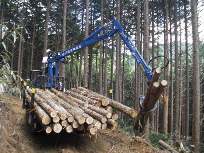 枝払い・造材した間伐材をH20導入グラップル付きフォワーダを使ってトラックが入れる林道まで小運搬している様子です<br>【森プロ団地】
